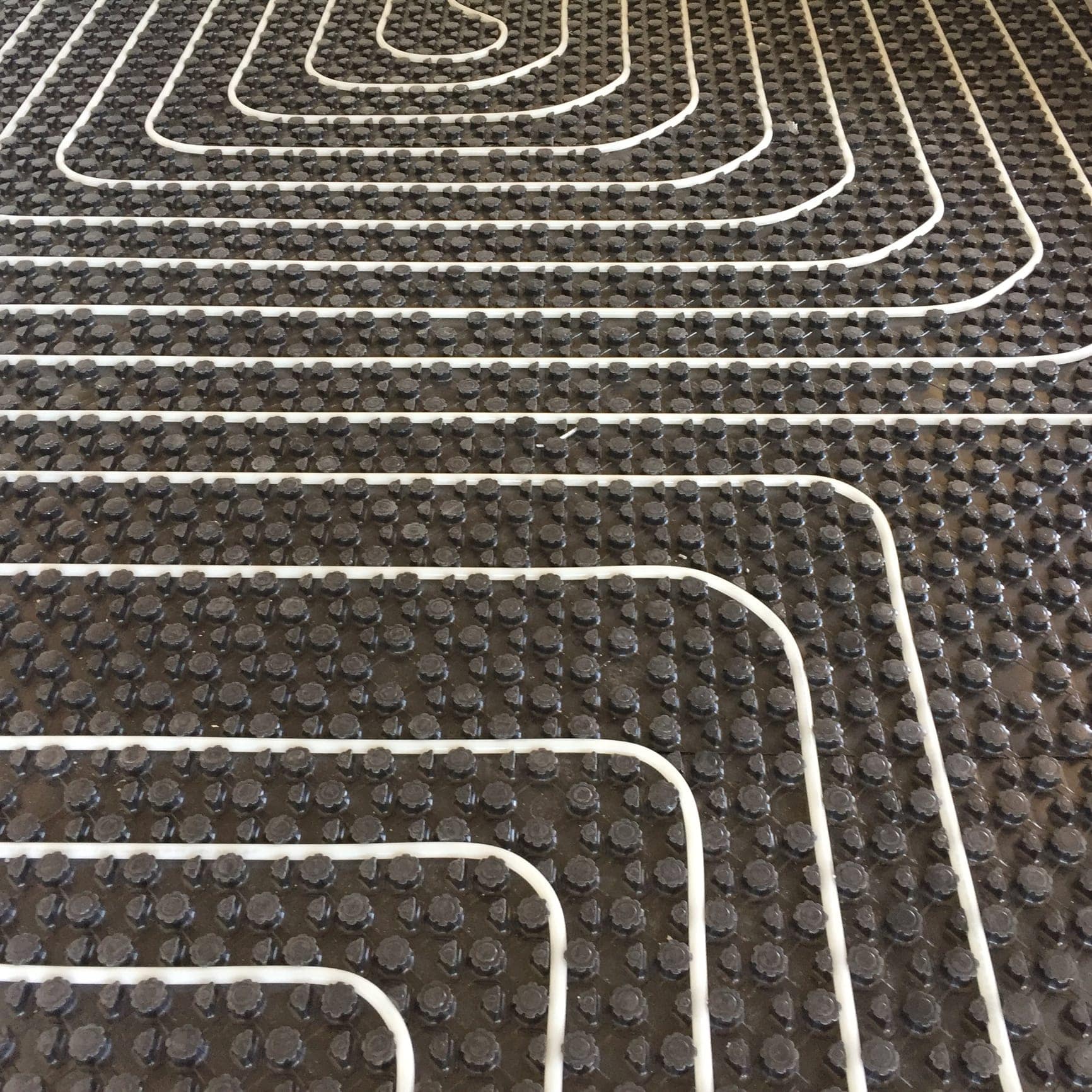 White hydronic radiant-heating tubing secured in a floor panel system
