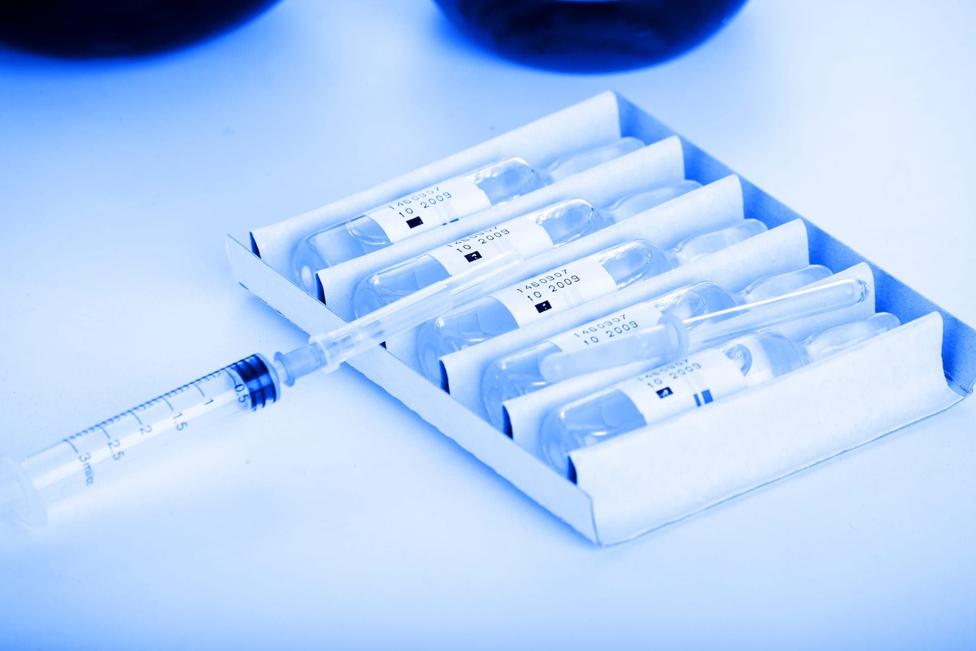 Glass sample ampoules and a syringe arranged on a laboratory tray