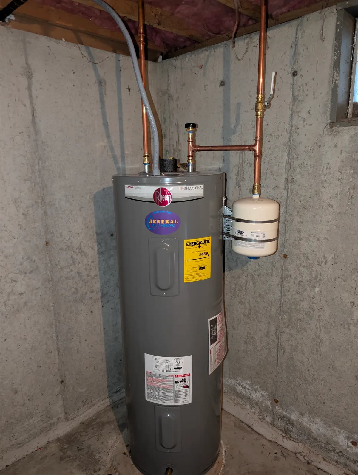 Rheem Classic electric water heater with thermal expansion tank installed by Jeneral Plumbing in a Massachusetts basement