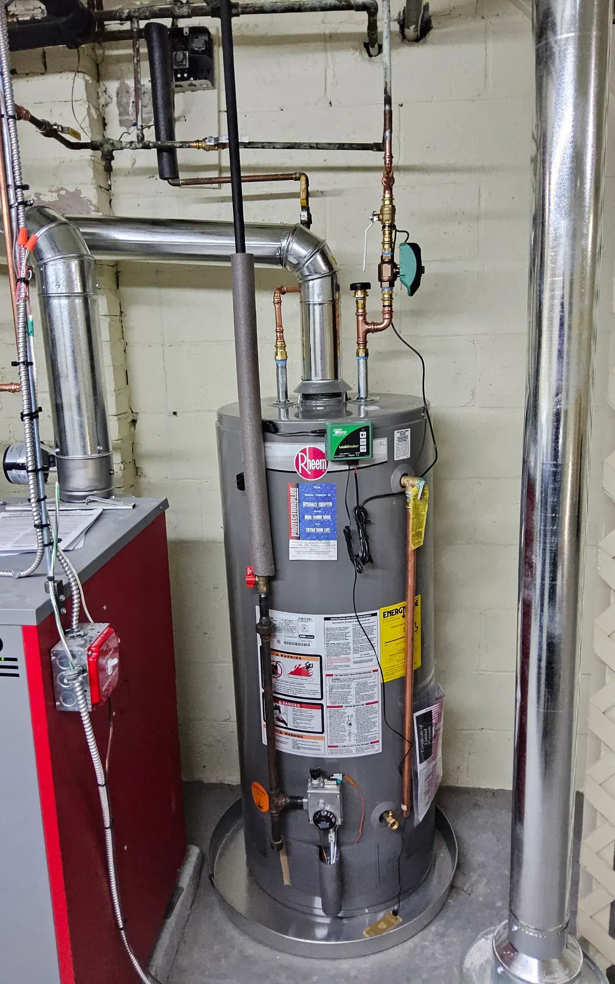 Rheem chimney-vented gas water heater with draft hood and metal flue connector venting into a chimney in a Massachusetts basement