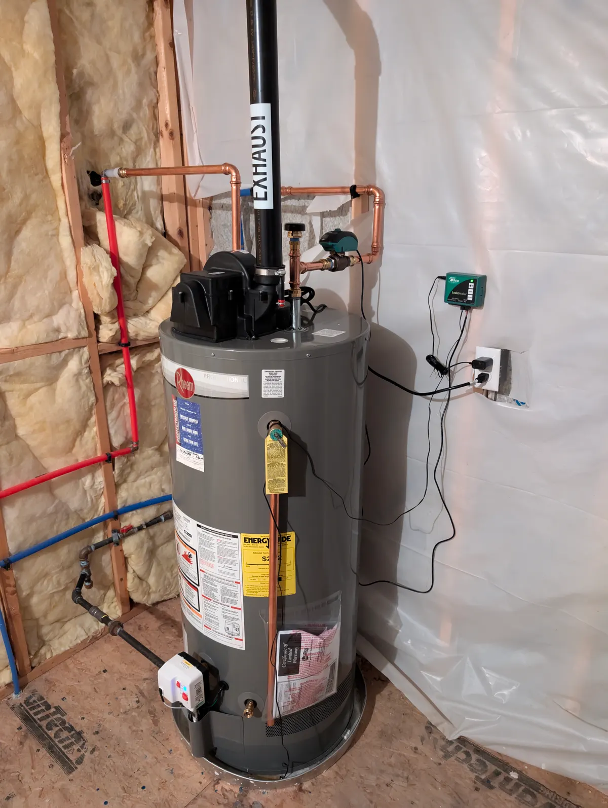 Rheem Professional power-vent gas water heater with top-mounted exhaust blower, vent piping, and leak detection in a Massachusetts basement